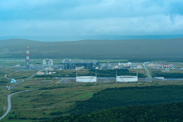 Fototapeta na wymiar aerial view of plant for the production of liquefied natural gas in a natural area against the backdrop of mountains