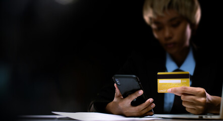 Business woman hold gold credit card and shopping online with internet financial banking payment when purchasing. Technology help person shopping at home in e-commerce store on mobile phone or laptop