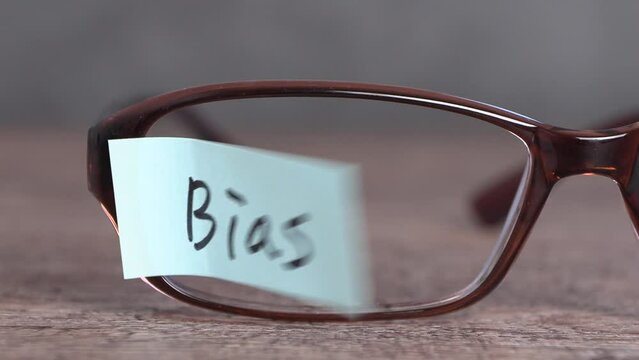 Pieces of paper and eyeglasses with a 'Bias' swaying in the wind.
