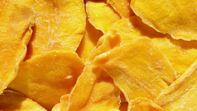 Dried mango slices close-up on a white. Top view. Closeup. Mango chips background. Dehydrated crispy fruit slices, pieces. Heap of sun-dried yellow fruit. Healthy meal. Top view, flat lay. 4K Footage.