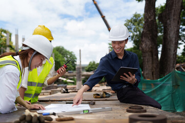 Structural engineer and architect discussing and working with blueprints at the outdoors construction site