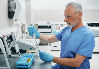 Mature male scientist with micropipette for test analyzes working at medical research laboratory....