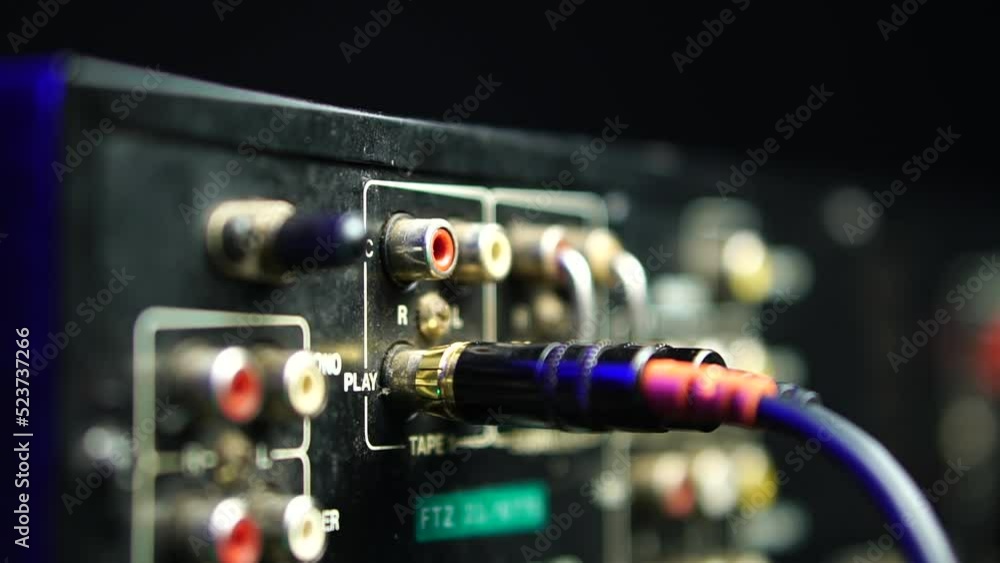 Poster connecting rca audio cable to play cassette tape input on analog amplifier close up