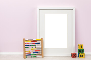 Background mockup template, white vertical transparent picture frame with matte and toddlers toys in front of pink wall