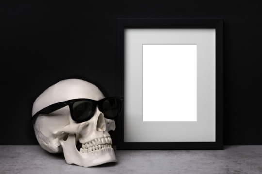 Background template with black vertical picture frame with matte and human skull with sunglasses in front of black wall
