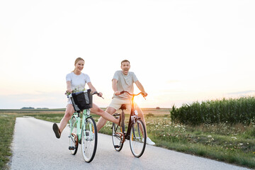 Wide shot of playful caucasian couple having fun on a bike on village road