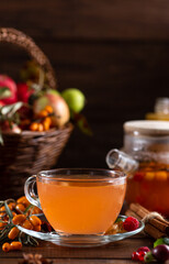 Berry tea. Sea buckthorn and raspberries in a glass teapot, cups with poured tea