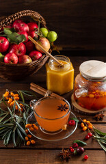 Autumn tea with berries and honey. Sea buckthorn and raspberries in a glass teapot, cups with poured tea