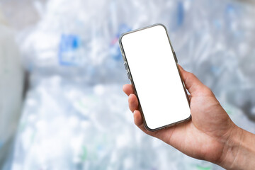 Man hand holding mobile phone with many PET bottles in background.