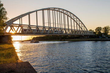 Train crossing the Amsterdam-Rhine Canal near Schalkwijk, Netherlands. Cargo ships on their way from Rotterdam to German.