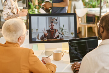 Rear view of business people having video call on computer with their colleague at office