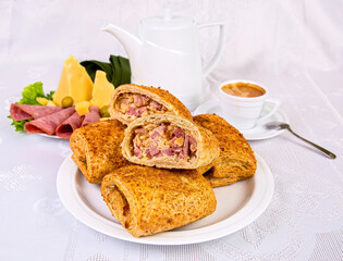 puff pastries stuffed with sausage and cheese, on a white dish, with a cup of coffee, on a white background