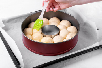 Cooking monkey bread consisting of yeast dough balls and brushing egg wash over before baking it in the ring pan