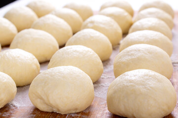 Yeast dough balls on the wooden board with flour. Preparing to bake buns, pizza or bread - 523748862