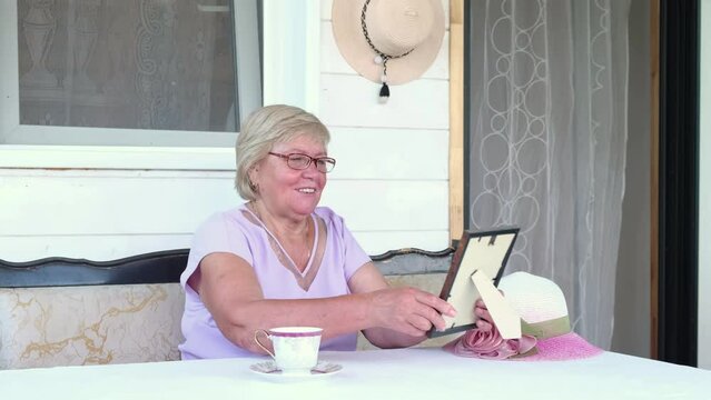 sad asian grandma looks at framed photo. Nice memories. an elderly woman lovingly looks at the photo.