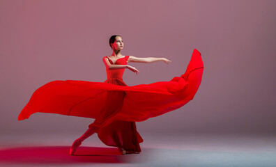 A young graceful ballerina, dressed in pointe shoes and a weightless red skirt, demonstrates her dancing skills. The beauty of classical ballet.