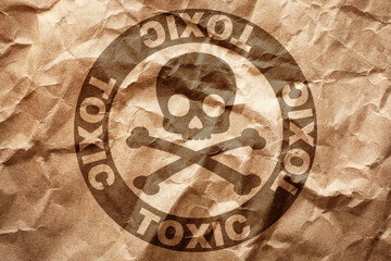 Fototapeta na wymiar Hazard warning sign (skull-and-crossbones symbol and word TOXIC) on crumpled kraft paper, top view