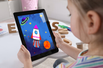 Little girl holding tablet with cute drawing at home. Child art
