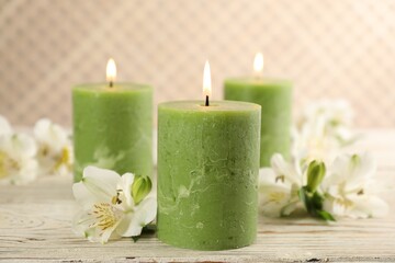 Burning candles and beautiful flowers on white wooden table
