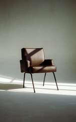 Stylish leather armchair in sunlight over white wall background.