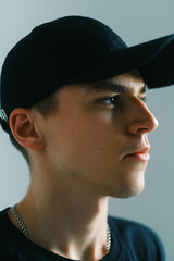 Portrait of stylish handsome caucasian man fashion model in t shirt and cap, studio shot.