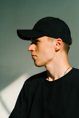 Portrait of stylish handsome caucasian man fashion model in t shirt and cap, studio shot.