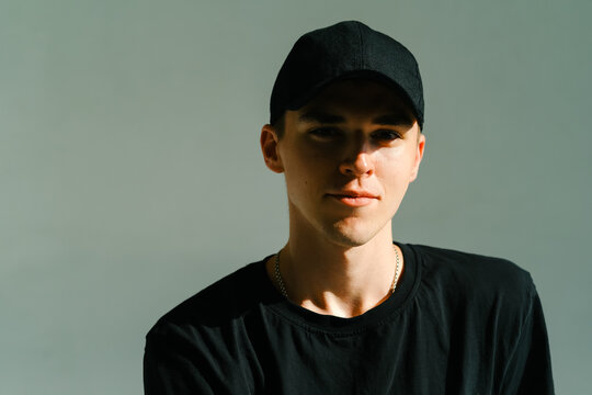 Portrait of stylish handsome caucasian man fashion model in t shirt and cap, studio shot.