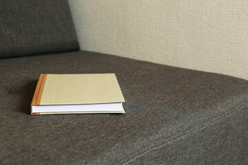 Hardcover book on grey sofa, space for text