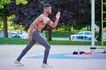 Young fit shirtless black man ready to run outdoors on sunny summer day. Fitness and sport...