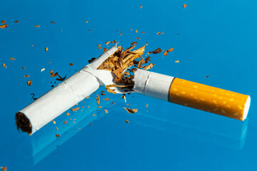 Broken cigarette on blue background. Stop smoking concept photography