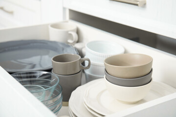 Fototapeta na wymiar Open drawer of kitchen cabinet with different dishware, closeup