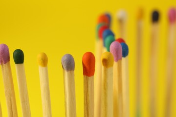 Matches with colorful heads on yellow background, closeup