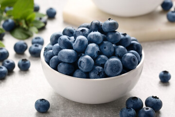 Tasty fresh blueberries on light grey table, closeup