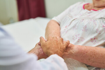 Nurses holding hands for comfort in the hospice - obrazy, fototapety, plakaty