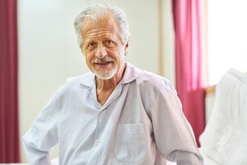 Old man as a senior sits in the bed of the nursing home