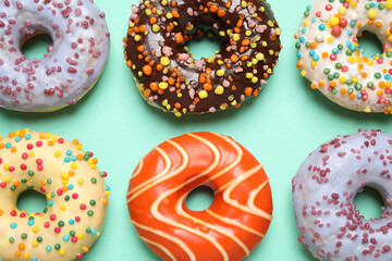 Delicious glazed donuts on turquoise background, flat lay