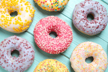 Delicious glazed donuts on blue wooden table, flat lay