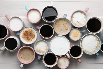 Many different cups with aromatic hot coffee on white wooden table, flat lay