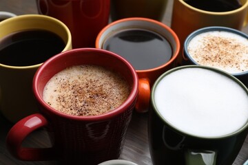 Many different cups with aromatic hot coffee on table, closeup