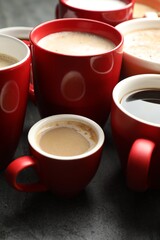 Many cups of different coffees on grey table, closeup