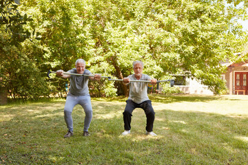 Two seniors doing squats in the park for fun