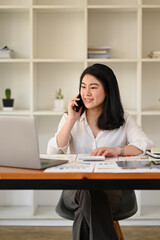 Obraz premium Millennial businesswoman having pleasant conversation, negotiations with business partner on mobile phone