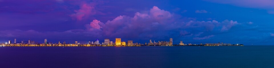 A view of Mumbai's Marine Drive closer to night with a few purple clouds. Overlooking the Back Bay, this area marks the southernmost part of the island city of Mumbai jutting out into the Arabian Sea. - obrazy, fototapety, plakaty