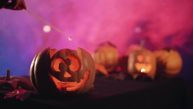 Halloween pumpkins with scary faces. Light a candle in a pumpkin. A hand sets fire to a pumpkin on Halloween. High quality  4k footage