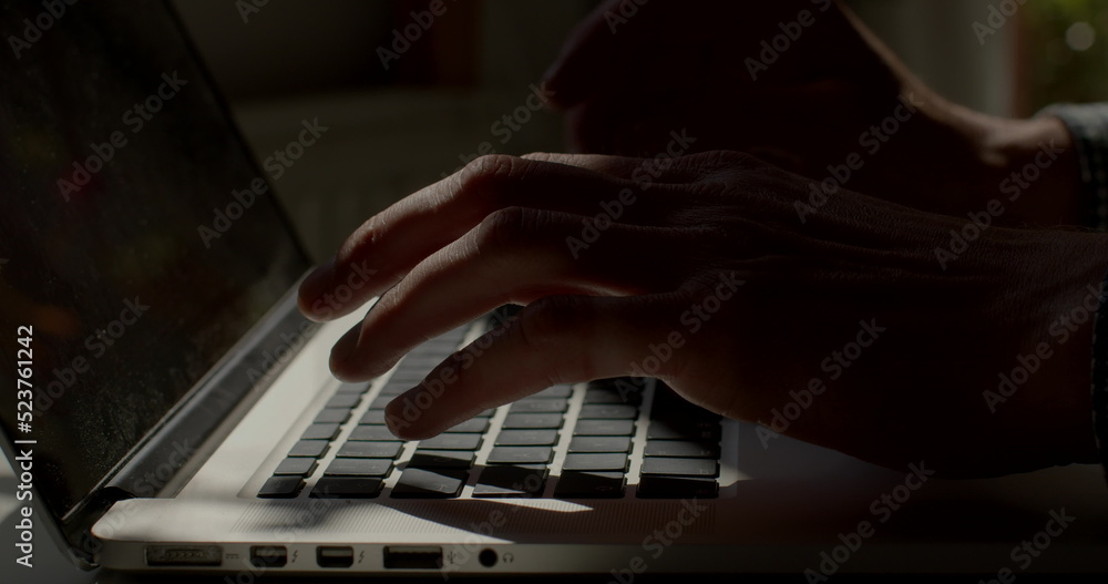 Fototapete light spot on a laptop keyboard. he presses buttons, prints text. writing a letter using a computer.