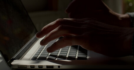 Light spot on a laptop keyboard. He presses buttons, prints text. Writing a letter using a computer. Finger movement using keys. A straight row of buttons in quick typing.