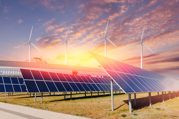 Set modern solar panels and wind turbines combined into station against blue sky with sunset