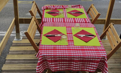 Table de restaurant en terrasse. Nappes à carreaux rouge et blanc.