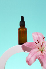 Cosmetic glass bottle with dropper for essential oils and serum on a podium with lily flower. Face and body care spa concept and natural cosmetics