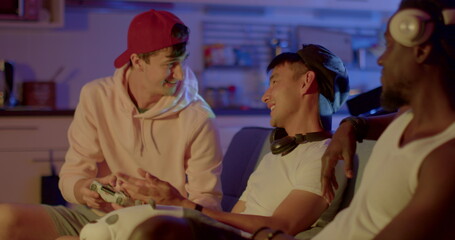 The guy lost the game, his friends support him. Night room. They exchange words during the game. Friendly company in the hostel of students. Red cap.